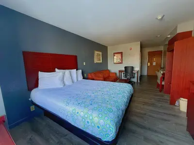 a bedroom with a bed and a living room at BlissPoint Inn & Suites, Northwood in Northwood
