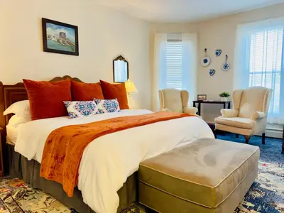 a bedroom with a large bed with orange pillows at Victorian Inn Bed And Breakfast in Marblehead