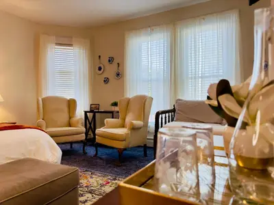 a living room with a bed and a couch and chairs at Victorian Inn Bed And Breakfast in Marblehead
