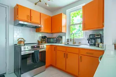 a kitchen with orange cabinets and a stove at Jungle House Columbus Short North Downtown Free Parking - Steps to Convention Center & Nationwide Arena - 2BR Luxury Home - Sleeps 8 - Over 5,800 Five Star Stays in Columbus