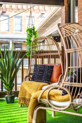 a porch with a rattan chair and a swing at Jungle House Columbus Short North Downtown Free Parking - Steps to Convention Center & Nationwide Arena - 2BR Luxury Home - Sleeps 8 - Over 5,800 Five Star Stays in Columbus