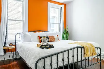 a bed in a room with an orange wall at Jungle House Luxury Stays - Columbus Downtown Short North in Columbus