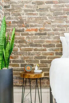 a table with a clock on it next to a brick wall at Jungle House Luxury Homes - Columbus Downtown Short North - Walk to Convention Center & Nationwide Arena - Sleeps up to 8 - Free Parking - Over 5,800 Five Stars in Columbus