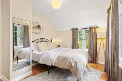 a white bedroom with a bed and a mirror at The Knocking Bird- Mins to CLE Clinic in Cleveland Heights