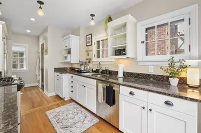 a kitchen with white cabinets and marble counter tops at The Knocking Bird- Mins to CLE Clinic in Cleveland Heights