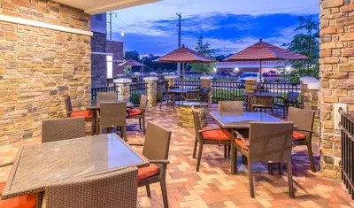 an outdoor patio with tables and chairs and umbrellas at Hyatt Place Canton in Lake Cable