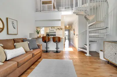 a living room with a brown couch and a staircase at 13 Mi to Port Clinton Lake Erie Getaway with Dock in Oak Harbor