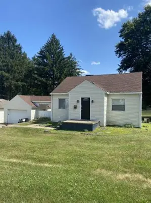 a white house with a yard with a grass field at North End Central Location in Zanesville