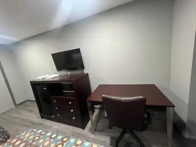 a desk with a tv and a table with a chair at Red Carpet Inn in Garfield Heights