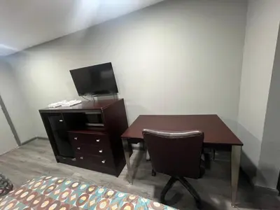 a room with a desk with a tv and a table with a chair at Red Carpet Inn in Garfield Heights