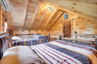 two beds in a log cabin bedroom with wooden ceilings at Chillicothe Cabin Near Hocking Hills State Park! in Chillicothe