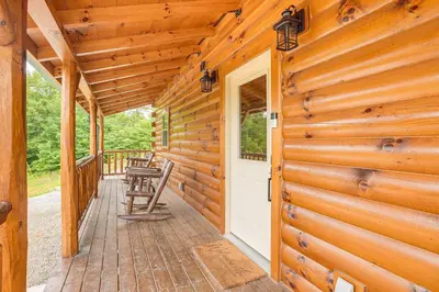 a log cabin porch with a white door and chairs at Chillicothe Cabin Near Hocking Hills State Park! in Chillicothe