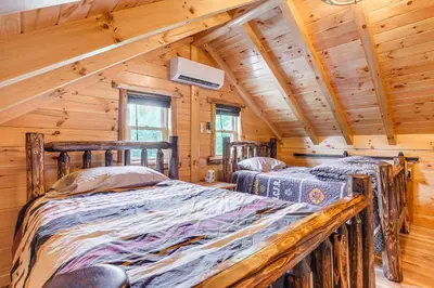 two beds in a log cabin bedroom with wooden ceilings at Chillicothe Cabin Near Hocking Hills State Park! in Chillicothe