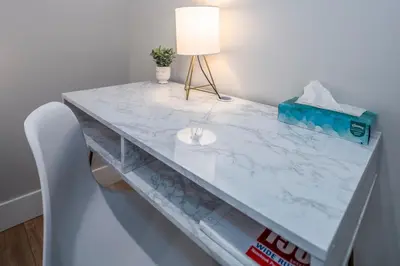 a white marble table with a lamp and a chair at Prime OTR, 3 Lux Queen Beds, Two 55in TVs, Steps to TQL, Findlay Market, Light Rail, Fast Wifi in Cincinnati
