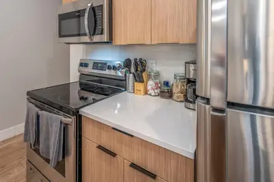 a kitchen with a stove and a refrigerator at Prime OTR, 3 Lux Queen Beds, Two 55in TVs, Steps to TQL, Findlay Market, Light Rail, Fast Wifi in Cincinnati