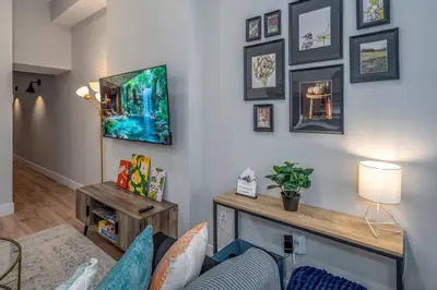 a living room with a tv on a wall at Central Over-the-Rhine, 3 Lux Queen Beds, Steps to TQL, Findlay Market & Light Rail, Fast Wifi, Sleeps 7ppl in Cincinnati