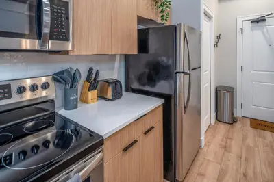 a kitchen with a stainless steel refrigerator and wooden cabinets at Central Over-the-Rhine, 3 Lux Queen Beds, Steps to TQL, Findlay Market & Light Rail, Fast Wifi, Sleeps 7ppl in Cincinnati