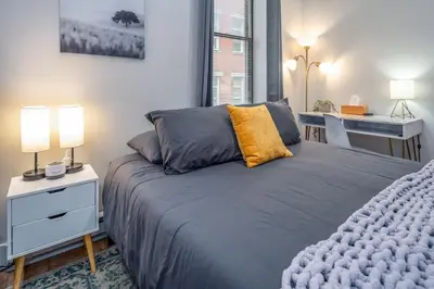 a bedroom with a bed and a desk and a window at Central Over-the-Rhine, 3 Lux Queen Beds, Steps to TQL, Findlay Market & Light Rail, Fast Wifi, Sleeps 7ppl in Cincinnati