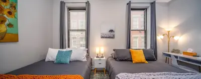 two beds in a small room with two windows at Central Over-the-Rhine, 3 Lux Queen Beds, Steps to TQL, Findlay Market & Light Rail, Fast Wifi, Sleeps 7ppl in Cincinnati