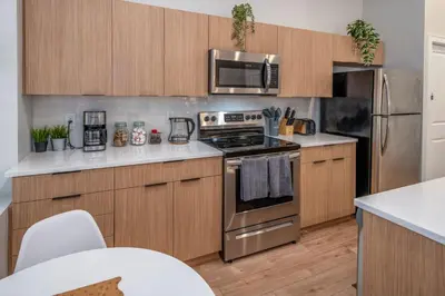 a kitchen with stainless steel appliances and wooden cabinets at Central Over-the-Rhine, 3 Lux Queen Beds, Steps to TQL, Findlay Market & Light Rail, Fast Wifi, Sleeps 7ppl in Cincinnati