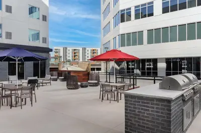 a patio with tables and umbrellas on a building at Homewood Suites By Hilton Newport Cincinnati in Newport