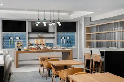 a kitchen with wooden tables and chairs and a counter at Homewood Suites By Hilton Newport Cincinnati in Newport