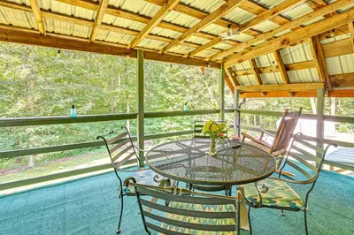 a table and chairs on the porch of a cabin at 5 Mi to Cave Run Lake Wellington Cabin with Deck! in Wellington