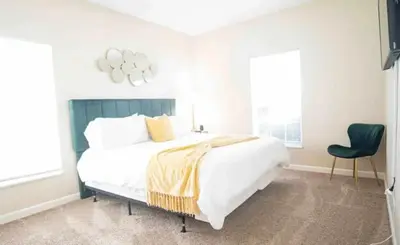 a bedroom with a large bed and a green chair at Cozy King 2 bedroom at Easton near Airport in Columbus