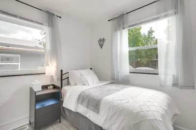 a white bedroom with a bed and two windows at Dayton Condo with Courtyard Less Than 3 to Downtown! in Dayton