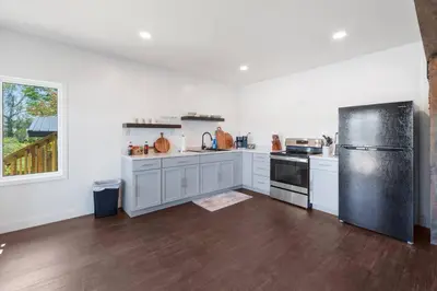 a kitchen with white cabinets and a black refrigerator at RiverSuite1 - A mesmerizing river and bridge view. in Russell