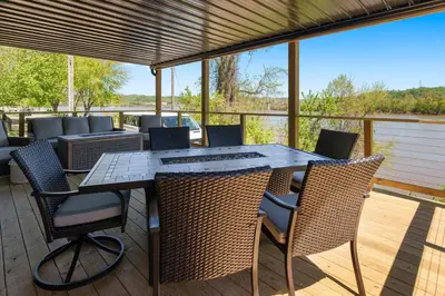 a patio with a table and chairs on a deck at RiverSuite1 - A mesmerizing river and bridge view. in Russell
