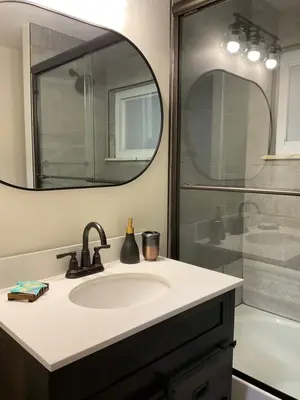 a bathroom with a sink and a shower with a mirror at Modern Farmhouse in Covington