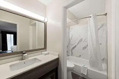 a bathroom with a sink and a toilet and a mirror at Suburban Studios Mason Near Kings Island in Mason