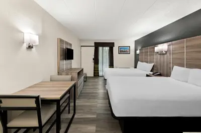 a hotel room with two beds and a table at Suburban Studios Mason Near Kings Island in Mason