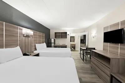 a hotel room with two beds and a flat screen tv at Suburban Studios Mason Near Kings Island in Mason