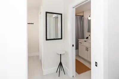 a white bathroom with a mirror and a stool at Inn At Fulton Boutique Hotel in Sandusky