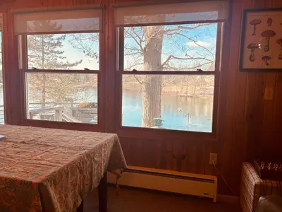 a room with two windows with a table and a view of a lake at Little Loch home in Burton