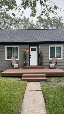a house with a porch with two chairs and a door at Captains Cove in Port Clinton