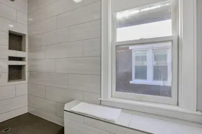 a white bathroom with a window and a bench at The Columbus Adventure in Columbus