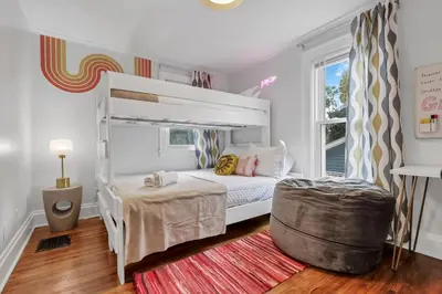 a bedroom with a white bunk bed and a ottoman at The Ohio State of Mind 5BR 2BA in Columbus