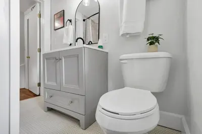 a white bathroom with a toilet and a mirror at The Ohio State of Mind 5BR 2BA in Columbus