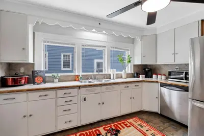 a kitchen with white cabinets and a large window at The Ohio State of Mind 5BR 2BA in Columbus