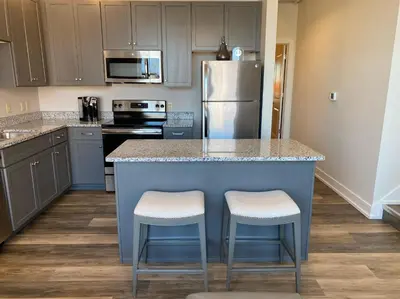 a kitchen with a blue island with two stools at Strongback Suite 207 in Adrian