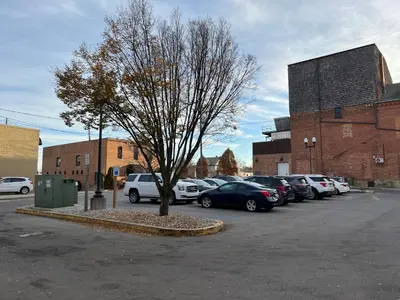 a tree in a parking lot with cars parked at Strongback Suite 207 in Adrian