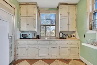 a kitchen with white cabinets and a window at The Retro Getaway in Columbus