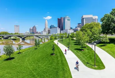 a park in the city with people walking and a bridge at The City Cottage - Unique and Cozy in Columbus