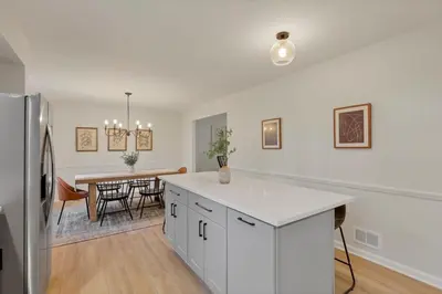 a kitchen with white cabinets and a dining room with a table at Gahanna Farmhouse - 4 Bed 2 Bath - INTEL in Columbus
