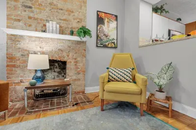a living room with a yellow chair and a brick fireplace at The Goodale Retreat - 2 BR 2Bath in Columbus