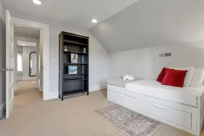a white bedroom with a large bed with red pillows at The Mohawk Masterpiece in Columbus