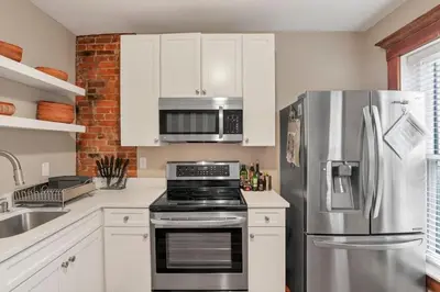 a kitchen with white cabinets and a stainless steel refrigerator at The Goodale House - 2 Units - 4 BR 5 Bath in Columbus